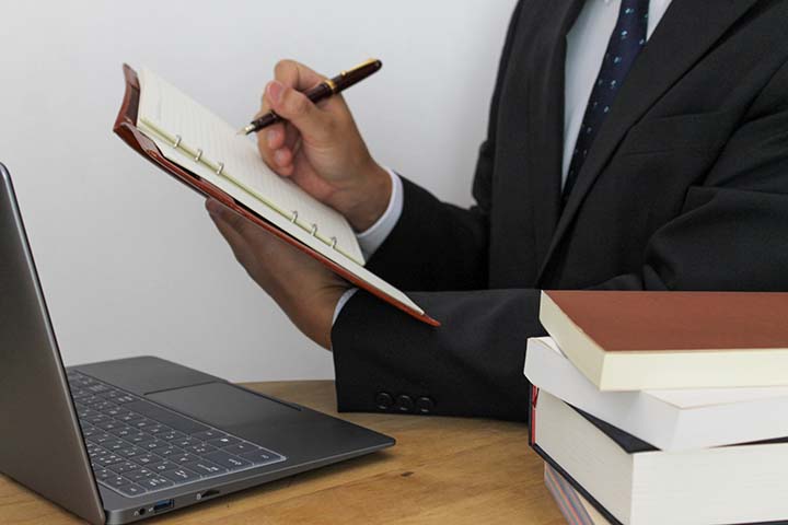 スケジュールを手帳に書き込むビジネスパーソンのイメージ