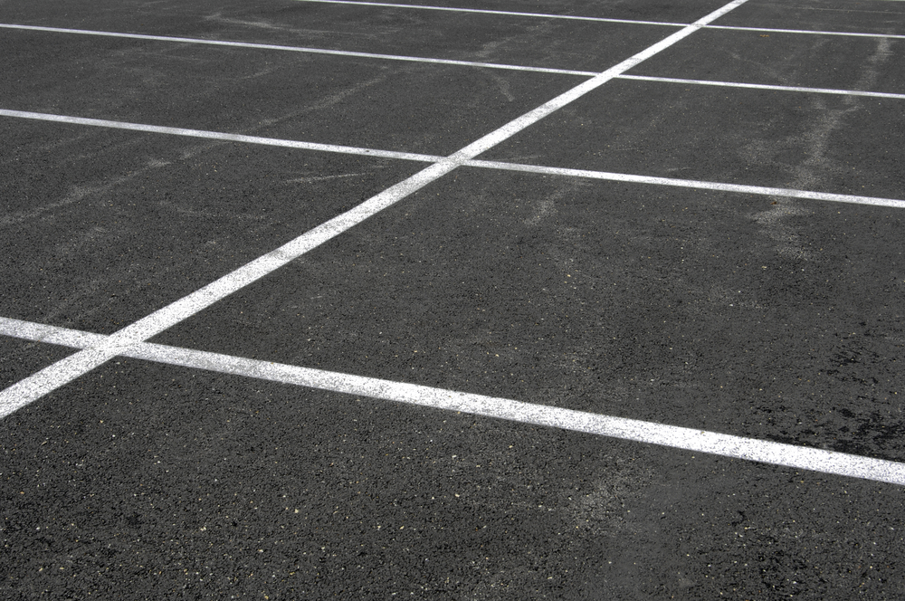Grid of white lines on weathered asphalt parking lot
