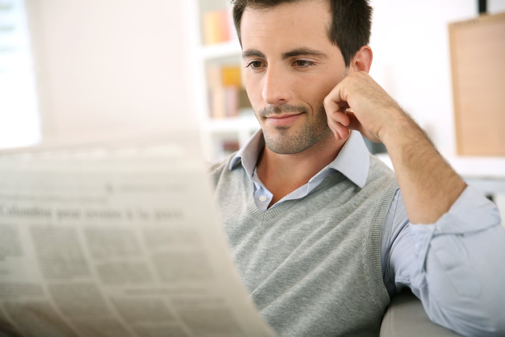 Man at home reading newspaper