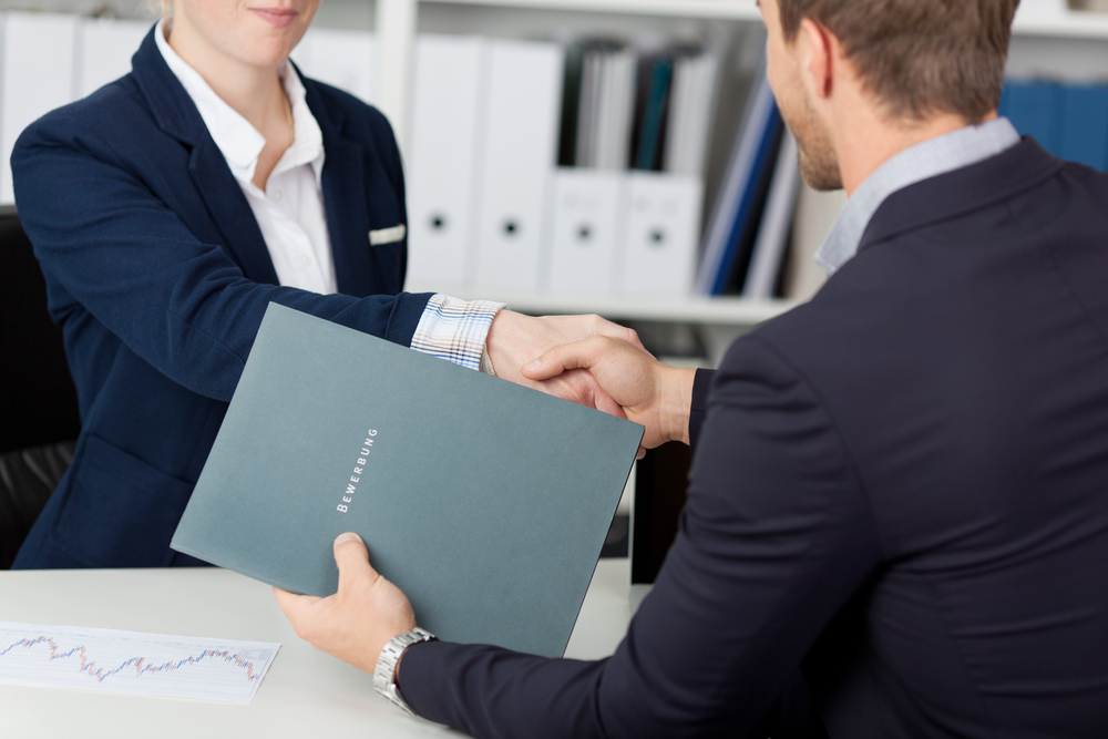 Midsection of a businessman shaking hands with a female interviewer in office