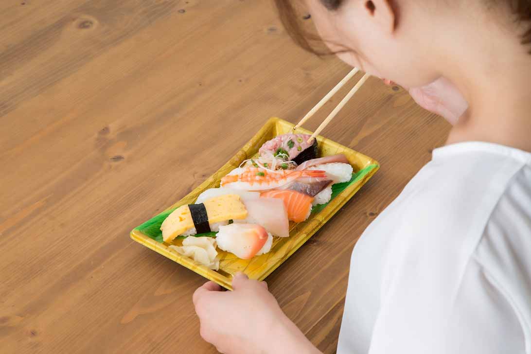 テイクアウトしたお寿司を食べる女性のイメージ テイクアウトしたお寿司を食べる女性のイメージ