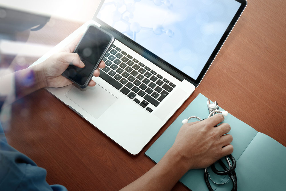 top view of Medicine doctor hand working with modern computer and smart phone on wooden desk as medical concept-1